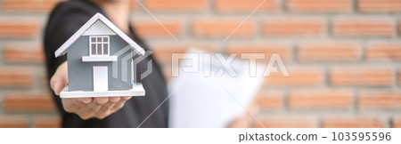 Home insurance concept and real estate. Businesswoman holding a house model working in investment about renting a house, buying a house, and home insurance 103595596