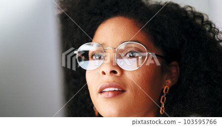 Businesswoman with trendy glasses reading information on a computer screen while working in an office. Closeup of one confident entrepreneur smiling while carefully analyzing reports and plans online 103595766