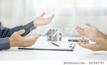 A real estate agent with a home model is talking to clients about renting a house and buying home insurance and contracting the contract after the formal negotiation is completed A real estate agent with a home model is talking to clients about renting a house and buying home insurance and contracting the contract after the formal negotiation is completed 103595797