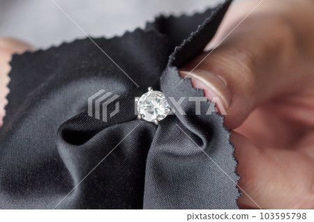 Jeweller cleaning jewelry diamond ring with fabric cloth 103595798