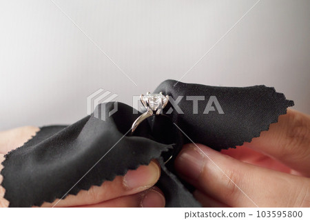 Jeweller cleaning jewelry diamond ring with fabric cloth Jeweller cleaning jewelry diamond ring with fabric cloth 103595800