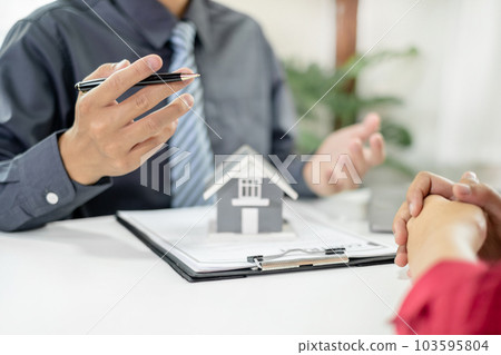 A real estate agent with a home model is talking to clients about renting a house and buying home insurance and contracting the contract after the formal negotiation is completed 103595804