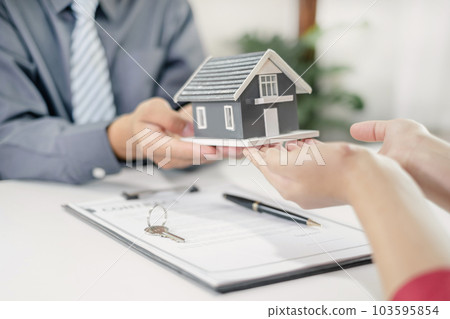 Real estate agent broker hand over the home to the new owner after completing the signing according to agreement renting a house and buy house insurance Home insurance concept 103595854