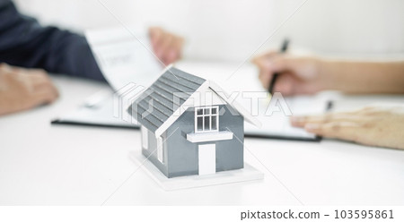 A real estate agent with a home model is talking to clients about renting a house and buying home insurance and contracting the contract after the formal negotiation is completed A real estate agent with a home model is talking to clients about renting a house and buying home insurance and contracting the contract after the formal negotiation is completed 103595861