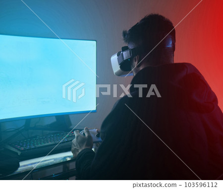 Man, computer with green screen, virtual reality and gaming, online streaming metaverse and mockup space. Digital world, VR goggles and controller, future technology and male streamer in dark room Man, computer with green screen, virtual reality and gaming, online streaming metaverse and mockup space. Digital world, VR goggles and controller, future technology and male streamer in dark room 103596112