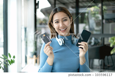 Asian girl shopping online holding credit and using smartphone enter their card number in the mobile phone app to purchase and payment in internet store Asian girl shopping online holding credit and using smartphone enter their card number in the mobile phone app to purchase and payment in internet store 103596117