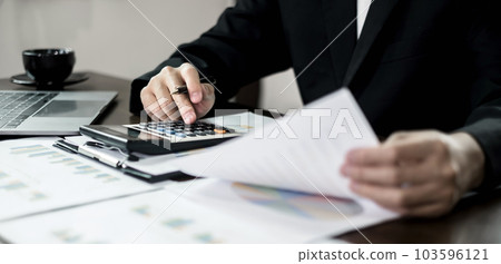 The businessman hand sits at their desks and calculates financial graphs showing the results of their investments planning the process of successful business growth The businessman hand sits at their desks and calculates financial graphs showing the results of their investments planning the process of successful business growth 103596121