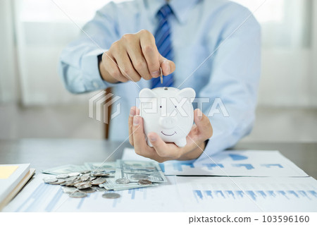 Man putting coin into piggy bank. Saving money with coins Step into a business that is growing to be successful and save for retirement concepts Man putting coin into piggy bank. Saving money with coins Step into a business that is growing to be successful and save for retirement concepts 103596160