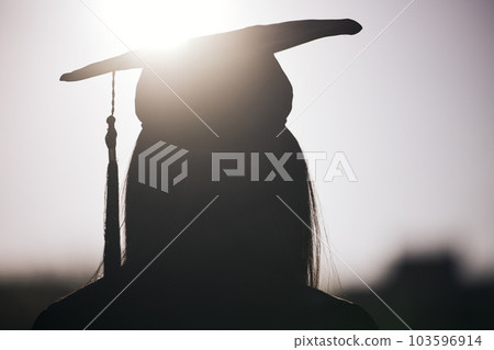 Graduation, education and silhouette of a student woman outdoor on university campus with lens flare. Future, college and scholarship with a female graduate standing outside at an event from the back 103596914
