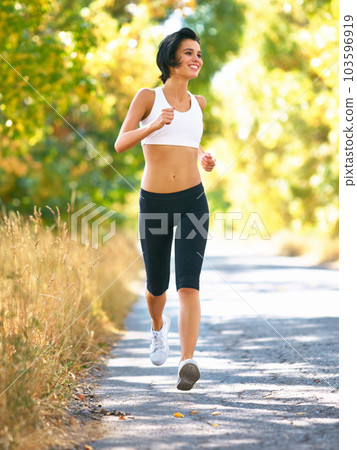 Woman is running in road, sport and fitness outdoor with fit body, healthy and active person. Cardio, exercise and training for race, young female runner in nature with workout for health Woman is running in road, sport and fitness outdoor with fit body, healthy and active person. Cardio, exercise and training for race, young female runner in nature with workout for health 103596919