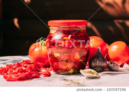 Dried tomatoes in a jar with spices and herbs. Autumn preparations, fermented vegetables. Home seasonal canning Dried tomatoes in a jar with spices and herbs. Autumn preparations, fermented vegetables. Home seasonal canning 103597206