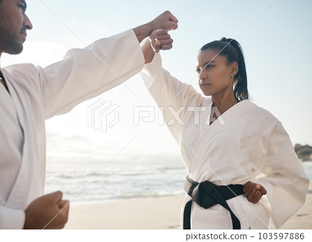 Going through their routines. Cropped shot of two young martial artists practicing karate on the beach. 103597886