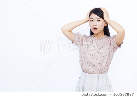 Surprised woman in her 30s holding her head in front of a white background Surprised woman in her 30s holding her head in front of a white background 103597957