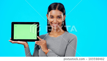 Mockup, green screen and face of a woman with a tablet isolated on a blue background in a studio. Branding, smile and portrait of an Indian girl holding technology with a blank screen for advertising 103598482