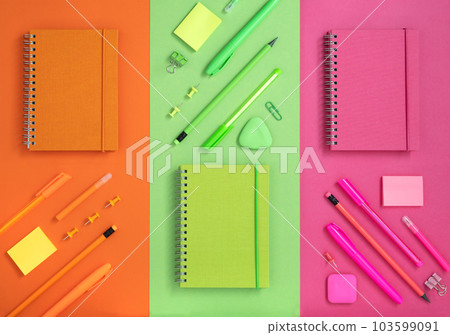 Flatlay knolling comosition of bright orange, green and pink stationery. 103599091