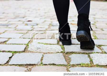 Close-up of a young woman's legs on a paved street in the old town. Journey. Tourism. Close-up of a young woman's legs on a paved street in the old town. Journey. Tourism. 103599141