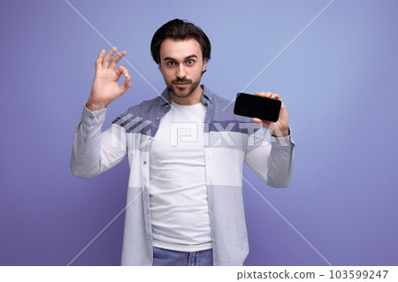 brutal brunette guy in casual style communicates using smartphone 103599247