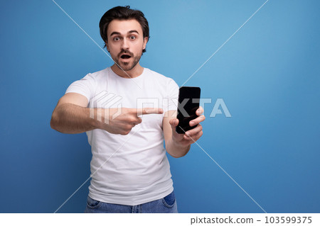bearded brunette guy in a white t-shirt shows a smartphone mockup 103599375