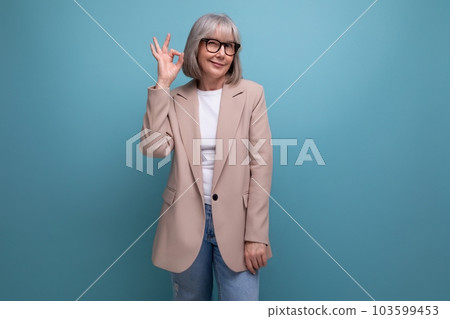 60s middle-aged woman in a business outfit feels confident on a studio background with copy space 103599453