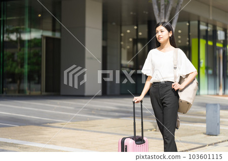 A businesswoman walking with a backpack and a suitcase 103601115