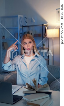 Think idea. Inspired woman. Study research. Puzzled lady spinning finger over head sitting desk with books laptop in light room interior. 103601602