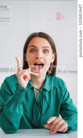 Smart idea. Video meeting. Strategy planning. Inspired emotional business woman in green blouse raising finger with pen in hand at office. Smart idea. Video meeting. Strategy planning. Inspired emotional business woman in green blouse raising finger with pen in hand at office. 103601647