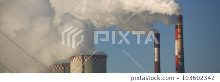 CHP cooling towers from which smoke is coming out against blue sky 103602342