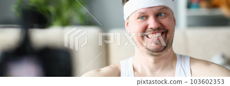 Smiling man is holding dumbbell and looking into camera Smiling man is holding dumbbell and looking into camera 103602353
