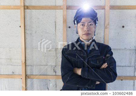 A male worker wearing fashionable denim work clothes and standing at a construction site A male worker wearing fashionable denim work clothes and standing at a construction site 103602486
