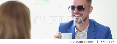 Smiling businessman drinking coffee and chatting with a woman in cafe 103602547