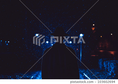 man detective agent in a hat and raincoat at night in a rainy city 103602694