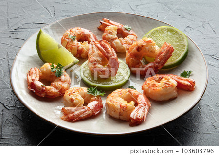 Shrimps. Cooked shrimp with lime on a white plate, on a black stone table Shrimps. Cooked shrimp with lime on a white plate, on a black stone table 103603796