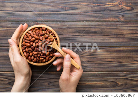 Woman hands holding a wooden bowl with peanuts. Healthy food and snack. Vegetarian snacks of different nuts 103603967