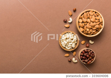 Assortment of nuts in wooden bowl on colored table. Cashew, hazelnuts, walnuts, almonds. Mix of nuts Top view with copy space 103604006