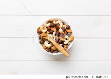 Assortment of nuts in wooden bowl on colored table. Cashew, hazelnuts, walnuts, almonds. Mix of nuts Top view with copy space Assortment of nuts in wooden bowl on colored table. Cashew, hazelnuts, walnuts, almonds. Mix of nuts Top view with copy space 103604013