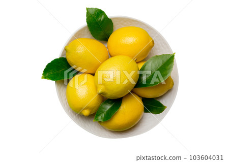 Fresh cutted lemon and whole lemons over round plate isolated on white background. Food and drink ingredients preparing. healthy eating theme top view with copy space 103604031