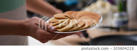 Woman holds plate with fresh delicious pancakes in kitchen 103604228