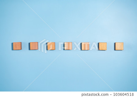 blank wooden cubes in a line shades ranging from dark to light beige on blue background. Minimalistic abstract concept representation of progress and diversity. Top view flat lay copy space 103604518