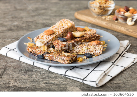 Various granola bars on table background. Cereal granola bars. Superfood breakfast bars with oats, nuts and berries, close up. Superfood concept Various granola bars on table background. Cereal granola bars. Superfood breakfast bars with oats, nuts and berries, close up. Superfood concept 103604530