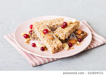 Various granola bars on table background. Cereal granola bars. Superfood breakfast bars with oats, nuts and berries, close up. Superfood concept Various granola bars on table background. Cereal granola bars. Superfood breakfast bars with oats, nuts and berries, close up. Superfood concept 103604531
