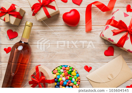 top view photo of st valentine day decor shopping, bag, wine, bottle, envelope, gift, box, candy and red heart on colored background with empty space. Frame background 103604545