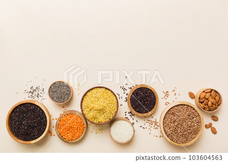 Various superfoods in smal bowl on colored background. Superfood as rice, chia, quinoa, lentils, nuts, sesame seeds, almonds. top view copy space Various superfoods in smal bowl on colored background. Superfood as rice, chia, quinoa, lentils, nuts, sesame seeds, almonds. top view copy space 103604563