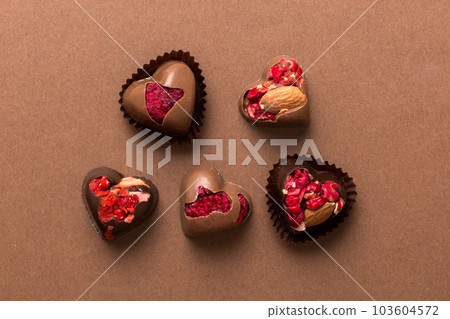 chocolate sweets in the form of a heart with fruits and nuts on a colored background. top view with space for text, holiday concept chocolate sweets in the form of a heart with fruits and nuts on a colored background. top view with space for text, holiday concept 103604572