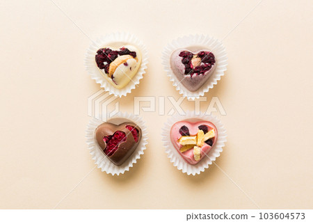 chocolate sweets in the form of a heart with fruits and nuts on a colored background. top view with space for text, holiday concept chocolate sweets in the form of a heart with fruits and nuts on a colored background. top view with space for text, holiday concept 103604573