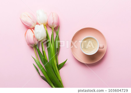 Spring background with flowers, a cup of coffee and a bouquet of pink and white tulips on colored table background with place for text. Copy space top view Spring background with flowers, a cup of coffee and a bouquet of pink and white tulips on colored table background with place for text. Copy space top view 103604729