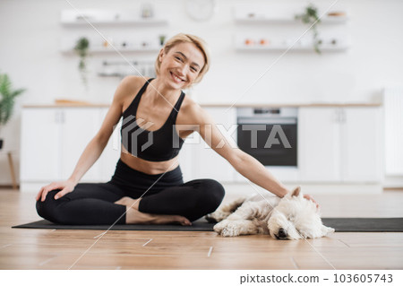 Yogini stroking dog during break in yoga session at home Yogini stroking dog during break in yoga session at home 103605743