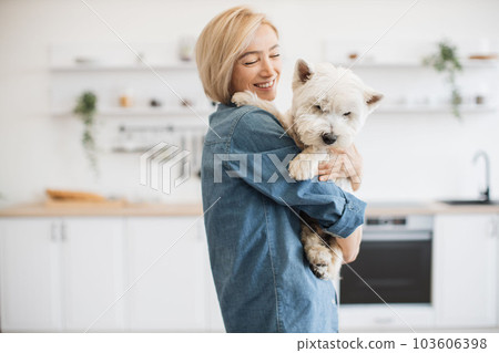 Female keeper holding dog on shoulder in room interior Female keeper holding dog on shoulder in room interior 103606398