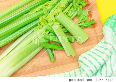 Fresh Celery Stem and Chopped Celery Sticks on Wooden Cutting Board 103606448