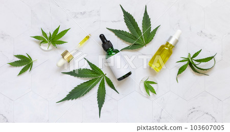 Cosmetic dropper bottles with blank label and pipette near green cannabis leaves. Mockup 103607005
