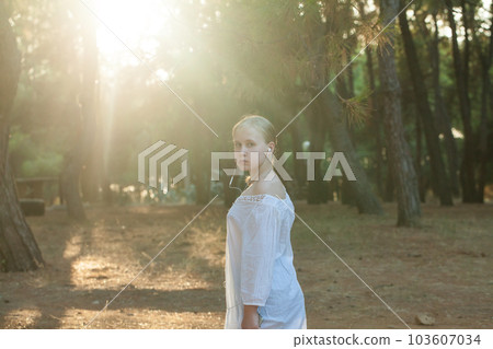 Pensive teenage girl in white shirt listen to music in headphones  103607034